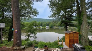 Une terrasse au bord du lac, avec des chaises Adirondack, un barbecue et un abri en bois.