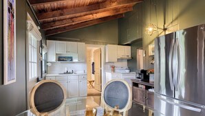 Une cuisine moderne avec des meubles blancs, un réfrigérateur en acier inoxydable et une table à manger en verre, assortie de chaises en bois.