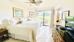 Une chambre à coucher comprenant un lit, un bureau, une télévision et un ventilateur de plafond.