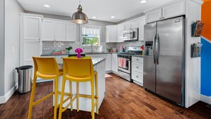 A modern kitchen with white cabinets, stainless steel appliances, and a wooden floor.