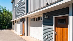 A two-story residential building with a garage, a front porch, and a driveway. - The Emerald Nest 3BR Townhome Near Downtown Beach Wineries (Traverse City)