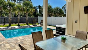 An outdoor pool area with a covered patio, chairs, and a table. - Sandy Palms ~ Pet-Friendly Coastal Retreat with Golf Cart & Game Loft (Panama City Beach)