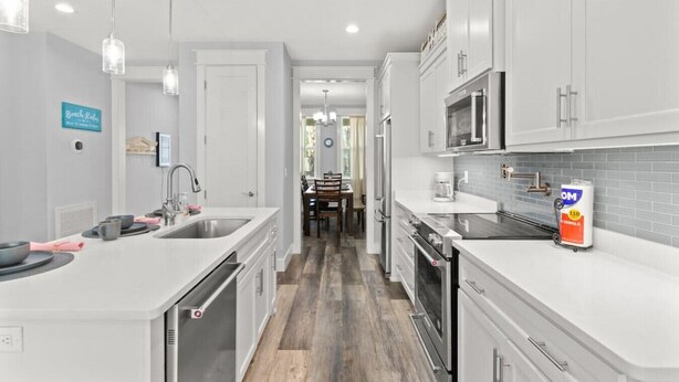 A modern kitchen with white cabinetry, stainless steel appliances, and a wooden floor. - Sandy Palms ~ Pet-Friendly Coastal Retreat with Golf Cart & Game Loft (Panama City Beach)