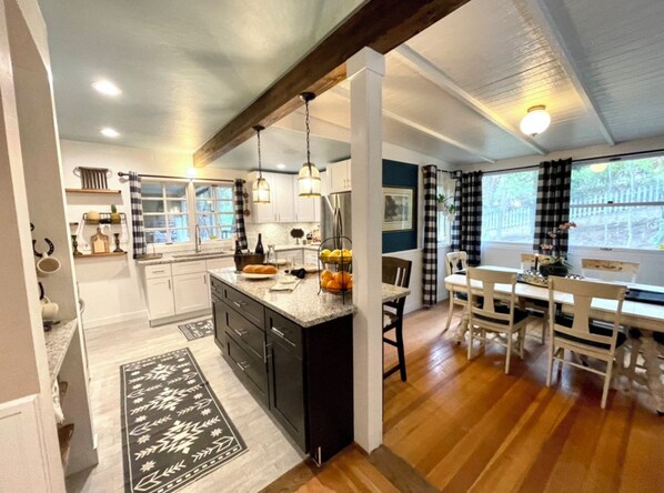 A modern kitchen with a central island, dark cabinetry, and pendant lighting.