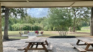 An outdoor patio area with two picnic tables and a swing set. - Secluded Whoop Acre Ranch SLEEPS 25-LOADED with entertainment (Bryan)