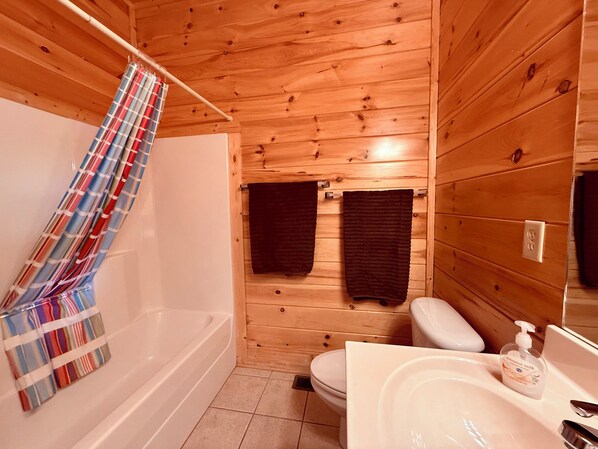 A wooden cabin bathroom with a bathtub, toilet, and sink. - VIEWS! Stunning 4BR Cabin w/GameRoom & Pool Access! Located 7 Mins from PF Pkwy! (Pigeon Forge)