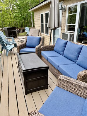 A deck with wicker furniture, a table, and chairs.
