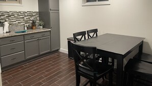 Una cocina con armarios de madera oscura, encimera de granito y una mesa de comedor con sillas.