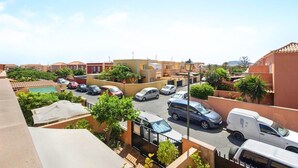 Un quartier résidentiel avec des voitures garées, une piscine et un ciel dégagé.