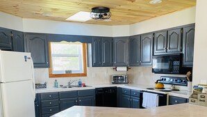 Una cocina con armarios oscuros, un refrigerador blanco, un microondas, una estufa y una isla grande con taburetes.