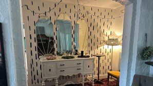 A room with a white dresser, a plaid rug, and a lamp.