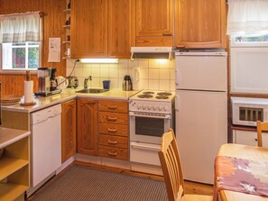 Une cuisine de taille réduite, dotée de meubles de rangement en bois, d’une cuisinière, d’un réfrigérateur et d’un four à micro-ondes.