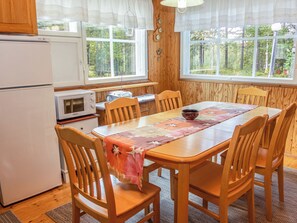 Une cuisine compacte avec des meubles de rangement en bois, un réfrigérateur, un four à micro-ondes et une table à manger avec des chaises.