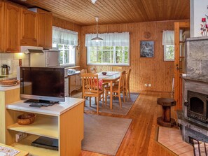 A cozy cabin interior with wooden walls, a dining area with a table and chairs, a kitchen with appliances, and a fireplace. - Peukaloinen b1 by Interhome (Kuusamo)