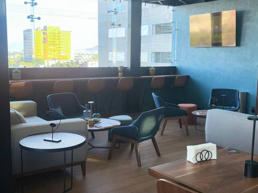 Un salón moderno con asientos, mesas y vistas a la ciudad.