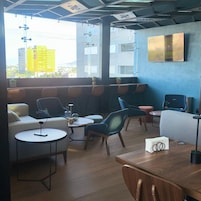 Un salon moderne doté de sièges, de tables et offrant une vue sur la ville.