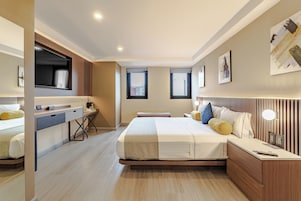 Une chambre d’hôtel moderne équipée d’un lit, d’une table de chevet, d’un bureau et d’une grande fenêtre.