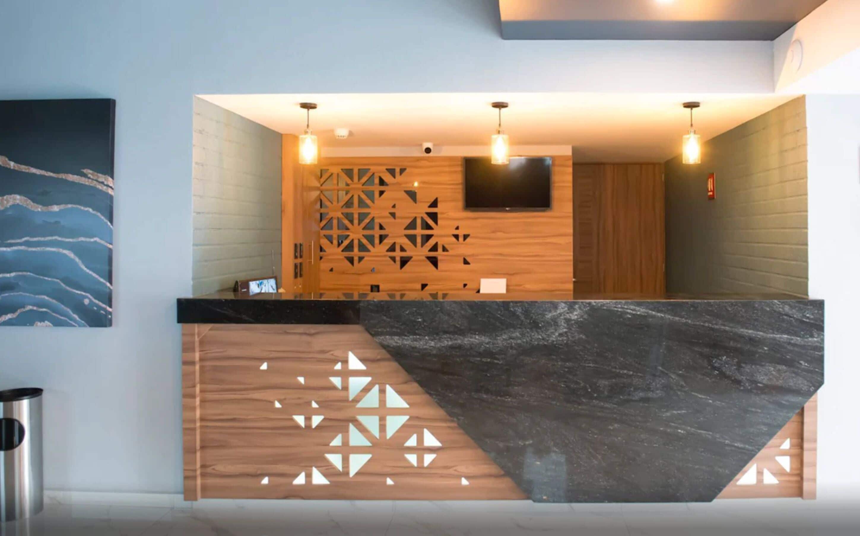 Zona de recepción con un panel de madera, una barra de mármol negro y un televisor montado.