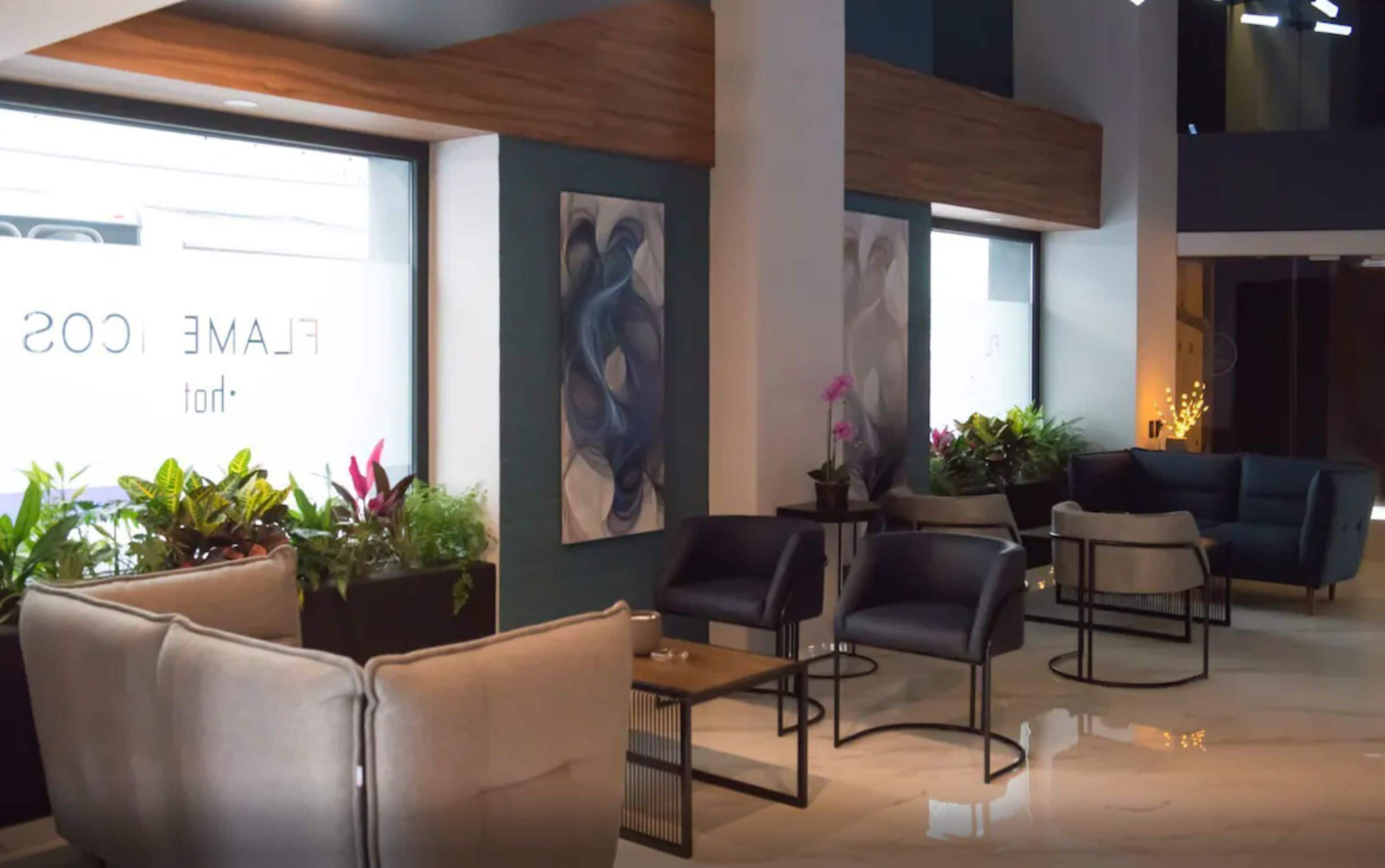 A modern lobby with leather seating, potted plants, and abstract wall art.