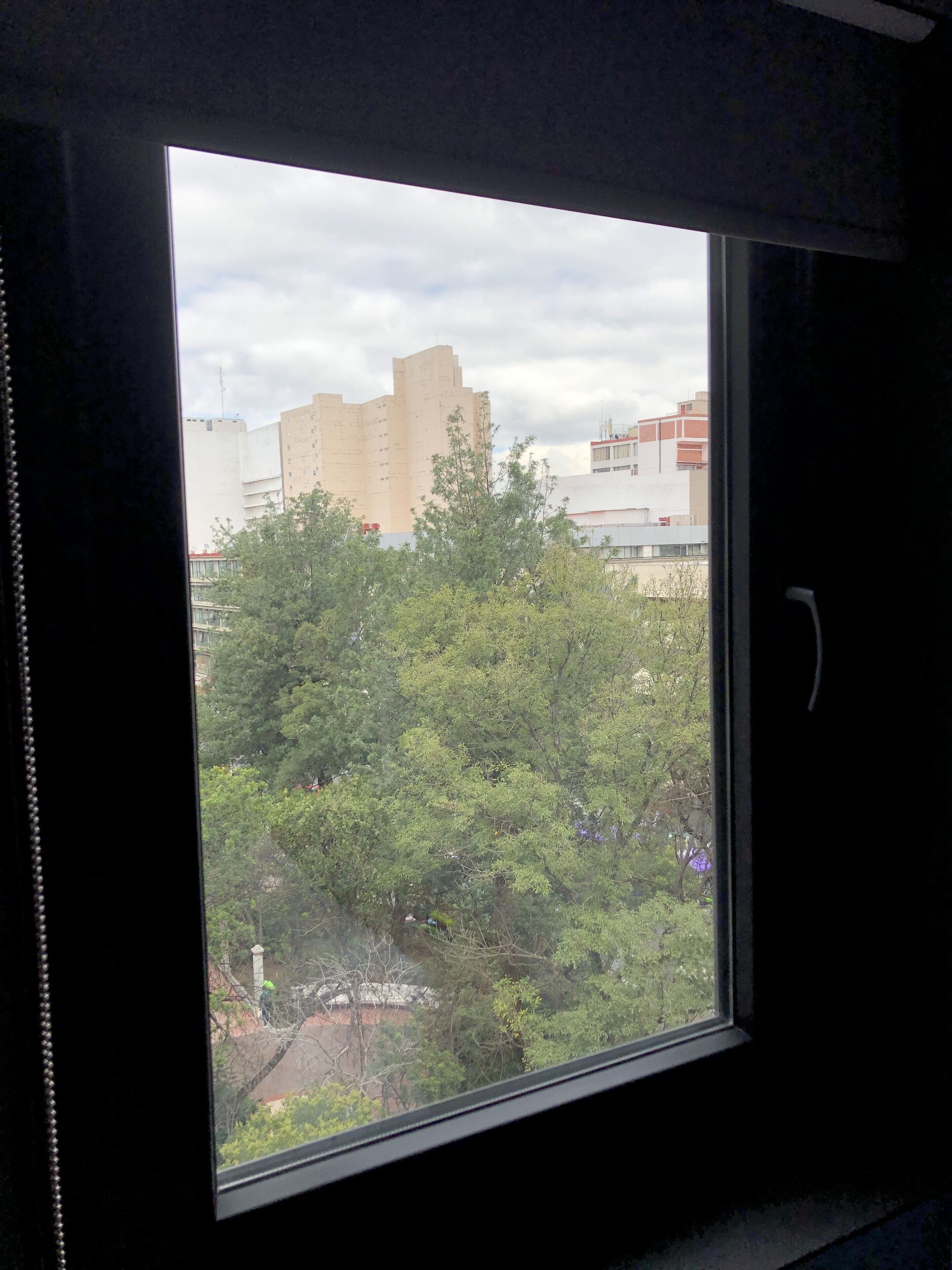 A window with a view of a building and trees.
