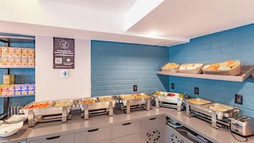 Disposición de un bufé con diferentes alimentos y un cartel encima.