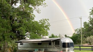 Ein Wohnmobil steht auf einer Wiese, im Hintergrund ist ein Regenbogen zu sehen.