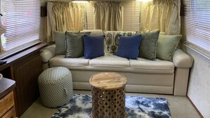 Ein gemütliches Wohnmobil-Interieur mit einer gepolsterten Sitzecke, einem Holztisch und einem gemusterten Teppich.