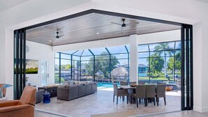 A spacious indoor area with a large glass wall, a pool, and outdoor furniture.