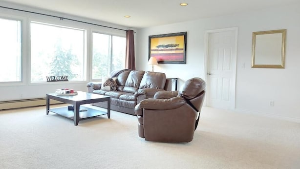 Un salón amplio con un sofá de cuero, un sillón reclinable y una mesa de centro.