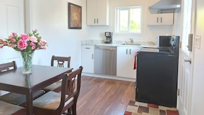 Una cocina compacta con armarios blancos, un refrigerador negro, una cafetera y un ventanal.