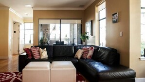 A living room with a black leather sofa, white ottomans, and a red and white polka dot rug. - Amazing Large Central Modern Flat - Great for Work + Families (San Francisco)