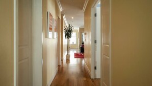 A hallway with wooden flooring, white walls, and a red rug leading to a room. - Amazing Large Central Modern Flat - Great for Work + Families (San Francisco)