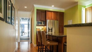 A kitchen with wooden cabinets, a stainless steel refrigerator, and a bar area with stools. - Amazing Large Central Modern Flat - Great for Work + Families (San Francisco)