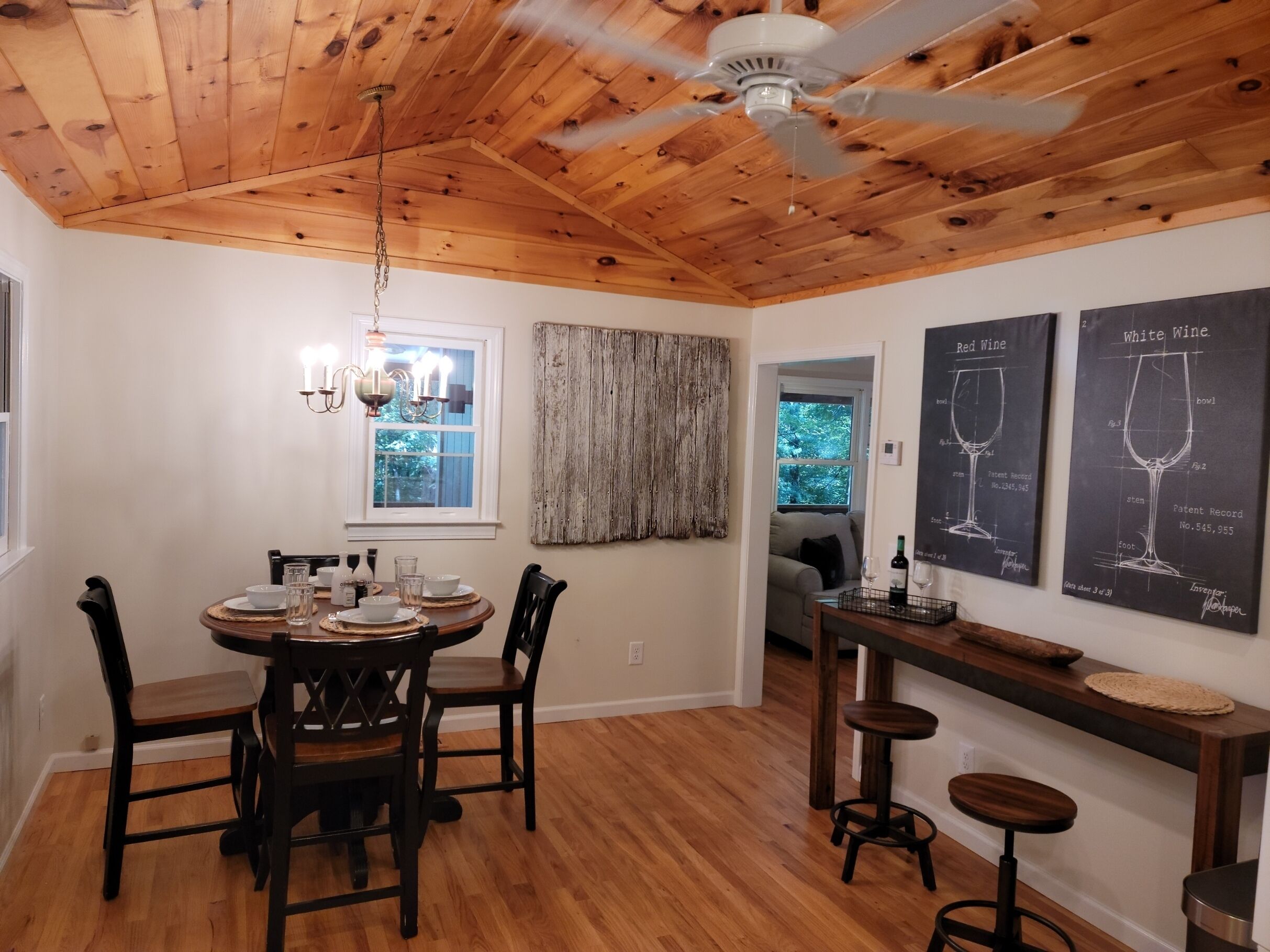 A dining area with a wooden ceiling, a chandelier, and a table set for four.