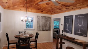 A dining area with a wooden ceiling, a chandelier, and a table set for four.
