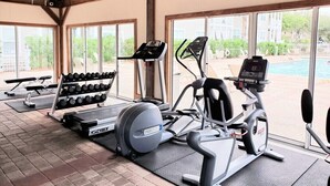 Ett gym med konditionsmaskiner, hantlar och en bänkpress.