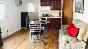 A compact living space with a dining area, kitchenette, and a sofa with a red pillow. - Wonderful Home (Pottstown)