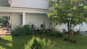 A two-story house with a covered porch, a small front yard with a tree, and a visible garage door. - Wonderful Home (Pottstown)