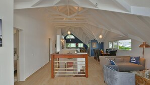 Un loft spacieux avec un haut plafond, une grande table en bois au centre, un canapé et un coin repas avec des chaises.