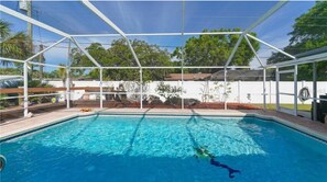 Ein Swimmingpool mit weißem Zaun und einer überdachten Liegefläche.