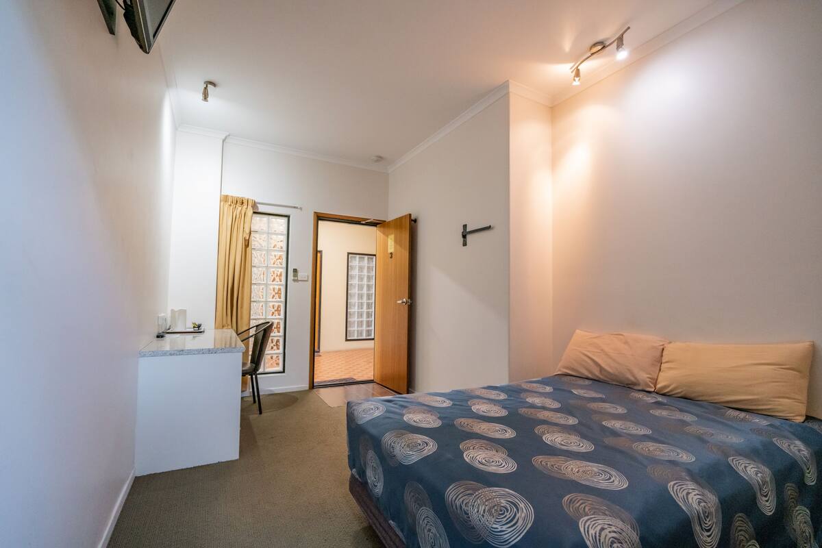 Un dormitorio con cama, escritorio y silla.