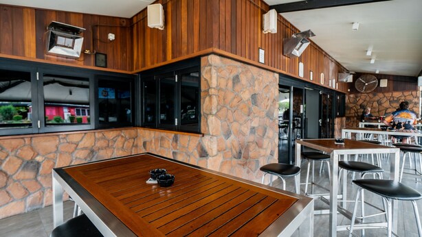 A modern restaurant with wooden tables and stone walls. - Capella Hotel Motel (Capella)