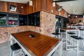 A modern restaurant with wooden tables and stone walls. - Capella Hotel Motel (Capella)