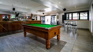 A billiards table in a room with a bar area and a window. - Capella Hotel Motel (Capella)