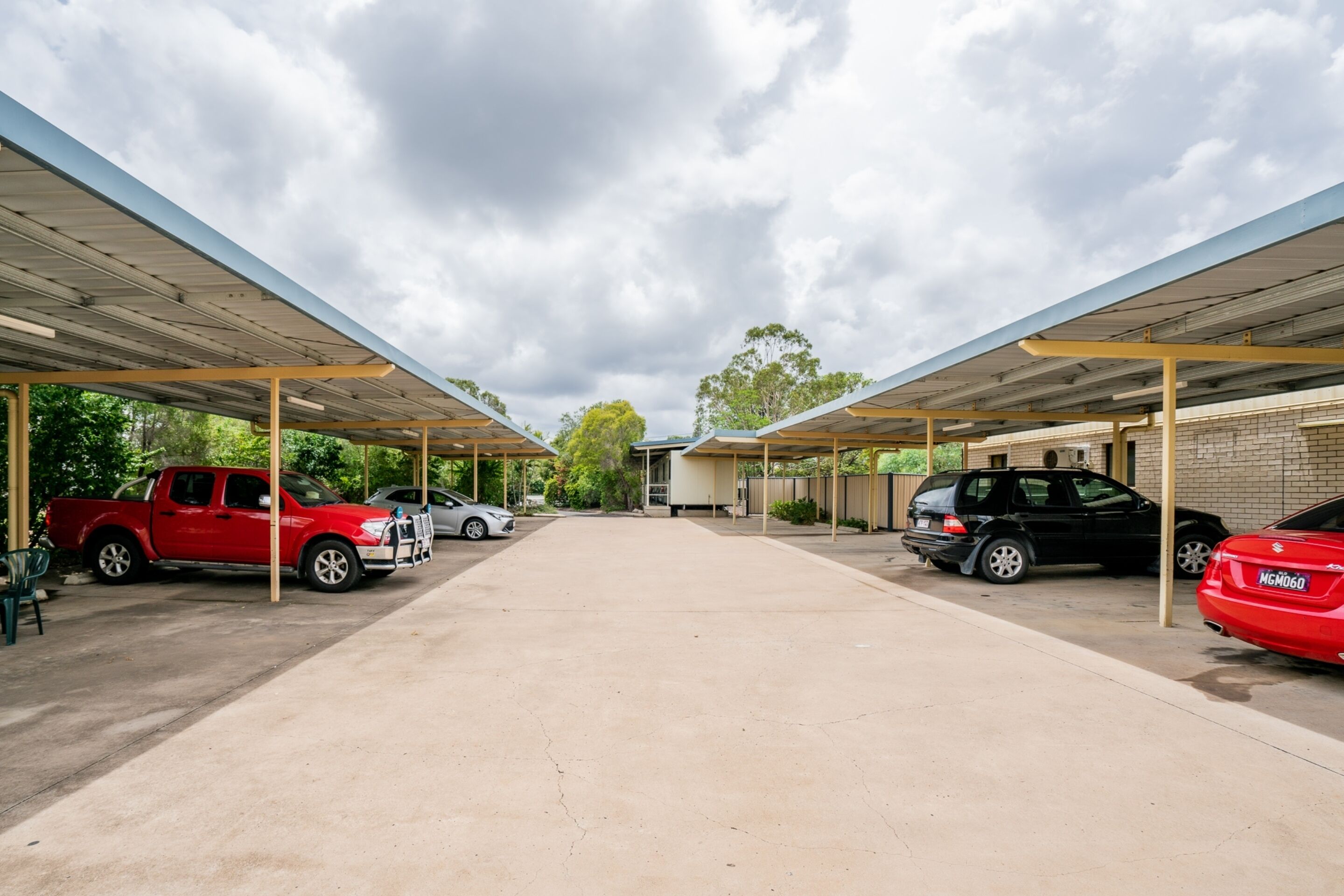 A covered parking area with multiple cars parked under a roof structure.
