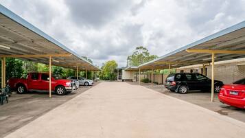 A covered parking area with multiple cars parked under a roof structure.