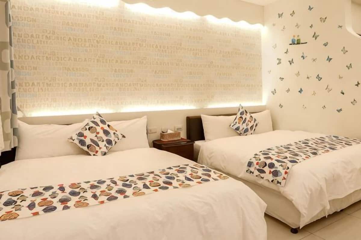 A hotel room with two beds, a nightstand, and a wall with butterfly decals.