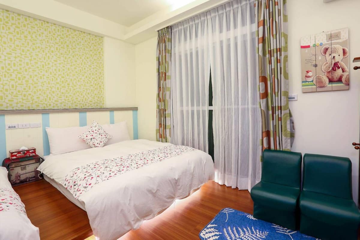 A hotel room with a bed, a chair, a small table, and a wall with a poster.