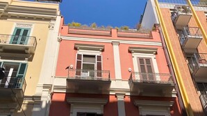 A multi-story building with balconies, a red facade, and a clear blue sky. - in the Heart of the City of Bari (Bari)