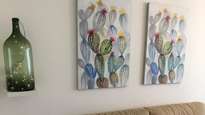 A living room with a beige sofa, two paintings of cacti, and a green bottle on the wall. - in the Heart of the City of Bari (Bari)